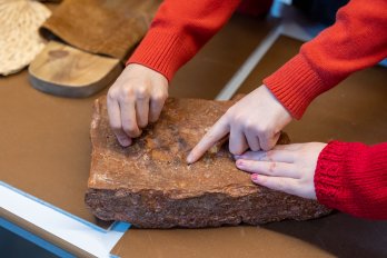Image: Children handling a tile with a pawprint embedded in it