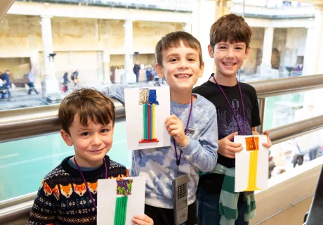 Three boys at the Roman Baths holding up their crafts